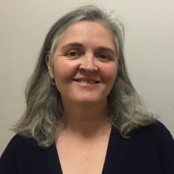 Lynn is a fair-skinned woman with straight silvery-grey hair and hazel eyes.