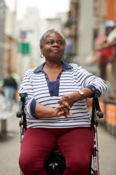 Woman seated in walker.