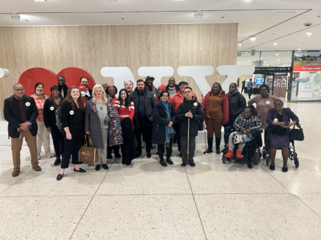 Group of 20+ advocates gathered in Albany in front of an I Love New York sign.