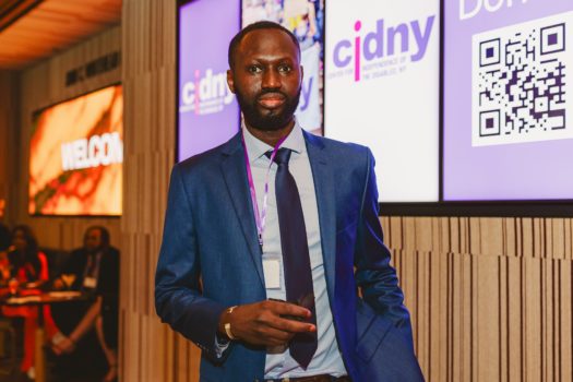 CIDNY's Mbacke Thiam standing in front of a screen with CIDNY logo.