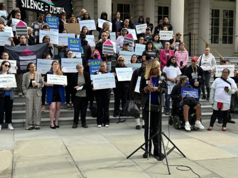 CIDNY's Dr. Sharon Mclennon Wier speaks outside of city hall at a Peers Not Police rally while advocates hold signs on City Hall steps.