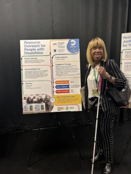 Dr. Sharon McLennon Wier standing beside a sign that says "Resource Outreach for People with Disabilities" at an NYC Civic Engagement Commission event in April 2025.