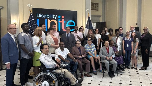 A group of advocates and elected officials gather in front of a Disability Unite banner for Disability Pride Month kickoff. A large group of advocates include NYC Comptroller Brad Lander, Representative Dan Goldmand, NYC Public Advocate Jumaane Williams, CIDNY's Dr. Sharon McLennon Wier and Arthur Schwartz, and many more.