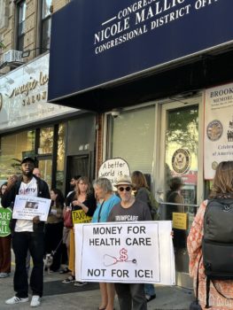 CIDNY staff with advocates outside local electeds office with advocates holding signs calling for health care funding.