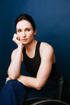 Headshot image of Jenna Bainbridge seated in a wheelchair looking forward.